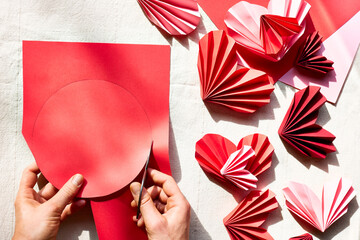 Woman hands making paper hearts. Origami garland. Symbol of love for valentines day, happy birthday, greetings, Mothers day, Women's day. Diy. Step by step. Step two.