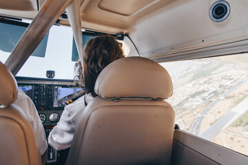 Inside view of the cockpit of an unrecognizable female student pilot flying her small plane holding the controls