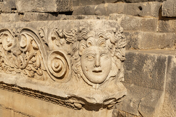 antique frieze with stone-cut mask in the ruins of the ancient city of Myra, Turkey