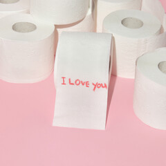 Valentines day creative layout with toilet paper rolls and handwritten message I love you on pastel pink background. 80s or 90s retro fashion aesthetic love concept. Minimal romantic idea.