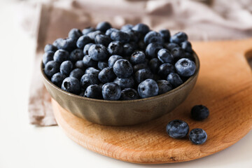 blueberries in a bowl on a cutting board on a white background