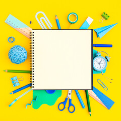 Fototapeta na wymiar Blank notebook and school supplies around on yellow background. Creative image with copy space.