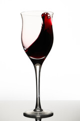 Swirl or movement of liquid in a glass of red wine. White background, vertical orientation. Concept of movement, elegance.