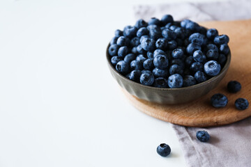 blueberries in a bowl on a cutting board on a white background