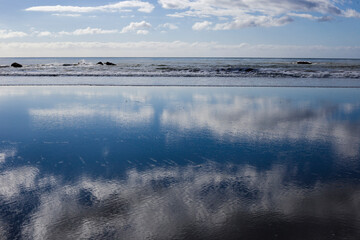 A glass-like reflection of the sky at the Pacific ocean beach