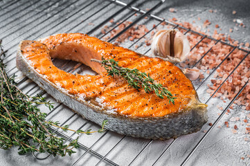 BBQ grilled Salmon Fish Steak on a grill with thyme and pink salt. White background. Top view
