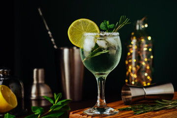 Fresh Mojito cocktail with lemon, rosemary, mint and ice in jar glass on dark blue background. Summer cocktail