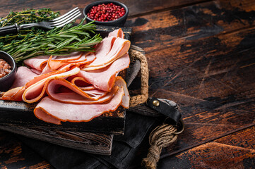 Italian Prosciutto cotto Ham slices in wooden tray with thyme and rosemary. Wooden background. Top...