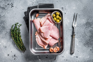 Ham slices in kitchen tray with herb and olives, Italian Prosciutto cotto. Gray background. Top view