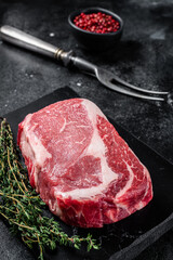 Rib eye, ribeye raw Steak, beef marbled meat with thyme and pink salt. Black background. Top view - obrazy, fototapety, plakaty