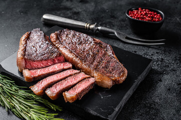 Grilled top sirloin or cup rump beef meat steak on marble board. Black background. Top view - obrazy, fototapety, plakaty