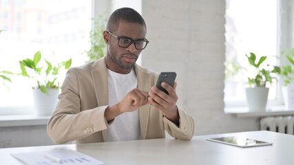 Attractive African Man using Smartphone in Office