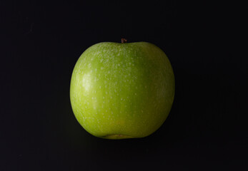 Green apple on a black background. Close-up