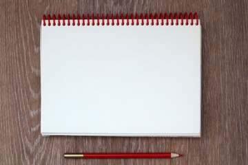 Mockup of open empty blank page of white spiral notepad with red pencil on wooden background. Copy...