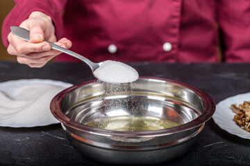Mixing raw egg whites in a bowl with added sugar