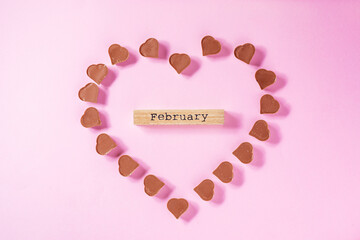 A heart shape made from chocolate pralines  for Valentine day or International woman's day or any celebration of love. Purple background, nice and simple concept. Top view.