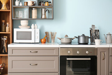 Interior of stylish kitchen with counter, microwave oven and shelves - obrazy, fototapety, plakaty