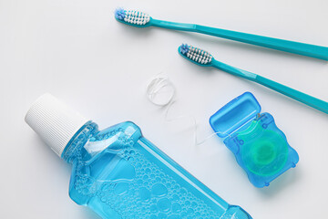 Dental floss with tooth brushes and rinse on white background