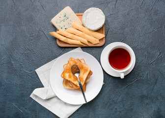 Bread with tasty pear jam, cheese and cup of tea on dark background