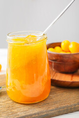 Obraz na płótnie Canvas Jar of tasty kumquat jam on light background