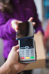 Smiling woman doing contactless payment while receiving package