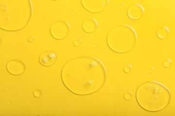 Drops of liquid transparent gel with bubbles on yellow background