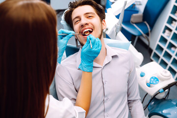 Young man at the dentist's chair during a dental procedure. Overview of dental caries prevention. Healthy teeth and medicine concept.