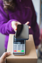 Smiling woman doing contactless payment while receiving package