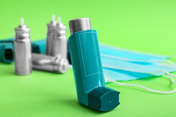 Asthma inhaler on green background, closeup