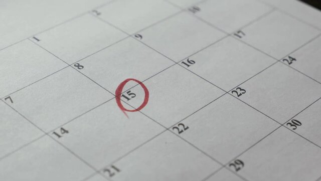 The hand circles the date in the calendar with a marker. The 15th day of the month.