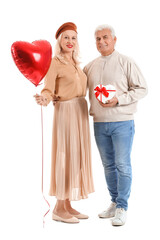 Happy mature couple with gift and balloon on white  background. Valentine's Day celebration