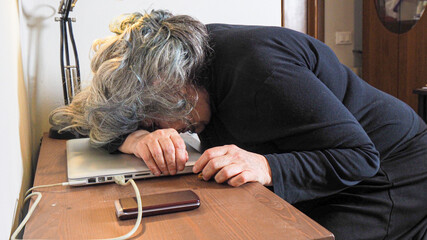 senior woman stressed by remote working, electronic hi tech devices and communication at home
