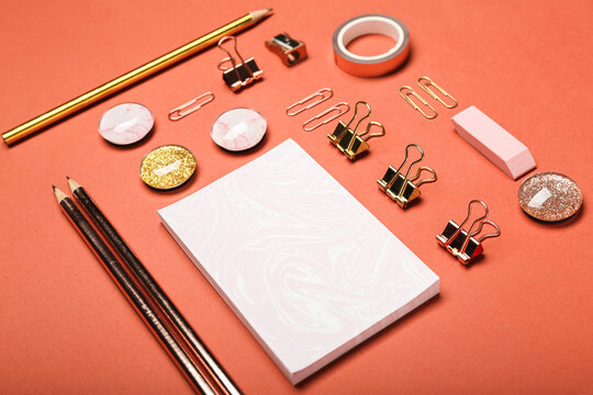 notepad and stationery neatly folded pencils, scotch tape, paper clips on orange background top view 
