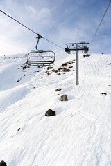 Fototapeta na wymiar Empty chair lift over snowy ski slopes in French alps 