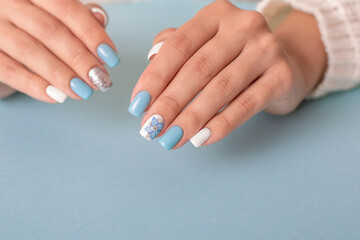Fototapeta premium Beautiful female hands with romantic manicure nails, blue and white gel polish