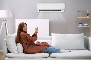 Young Woman Operating Air Conditioner
