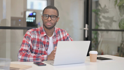 African Man Smiling at Camera while using Laptop