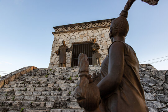 Statues representing a priest speaking with Maya people on the steps of a Mayan ruin seen on the island of Cozumel in Mexico