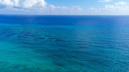 Vibrant turquoise blue ocean water in the Caribbean sea off the shore of Cozumel, Mexico. The sea is clear and you can see the coral reef under the surface.