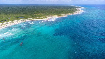 Lush jungle and beautiful turquoise Caribbean ocean water on the beach of Cozumel captured by a drone flying over Quintana Roo, Mexico.