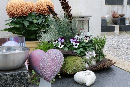 Herbstliche Grabgestaltung auf einem Friedhof in Österreich zu Allerheiligen, Grabschmuck mit Chrysanthemen und einem Herz