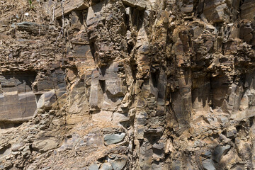 Granite wall. Close-up of a part of the rock destroyed by time. Dark gray stones