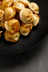 Fried dumplings on a black plate. Russian dish. Dumplings. Close up