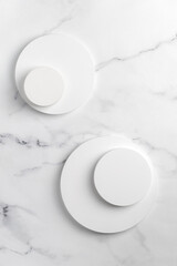 Podiums. White round podiums for presentation and cosmetic. Natural beauty pedestal on white marble background. Photography. Top view.
