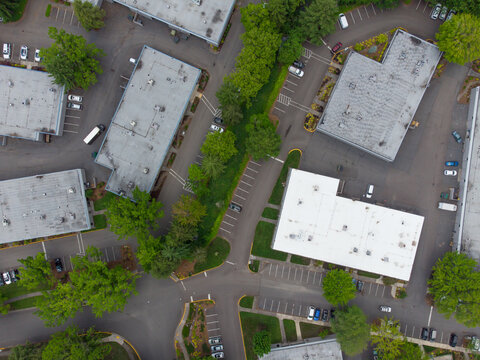 Aerial View. Small Suburb. Industrial Zone. Roofs Of Large One-story Rooms. Garages. Warehouses. Lots Of Greenery. Paved Roads. Cars. There Are No People In The Photo.