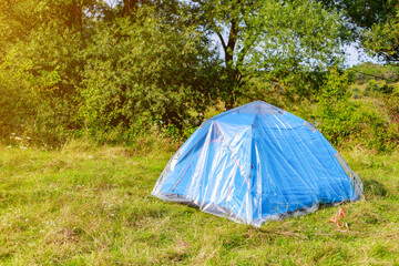 blue tent of a tourist in nature is covered with oilcloth or polyethylene film. Protection from...