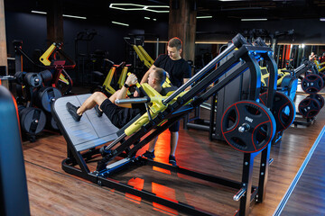 Sports exercises for a man with a trainer in the fitness room, male sport.
