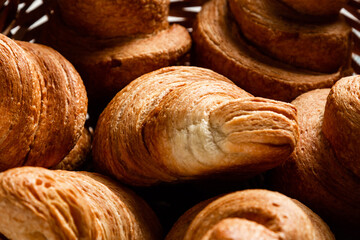 Croissants in a wicker basket on a wooden background. Close-up.
