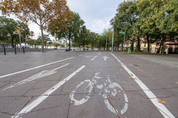 Obraz premium Barcelona, Spain - November 20, 2021: Cycle path in the city center empty due to the coronavirus pandemic. There are few people and vehicles on the street. Empty city