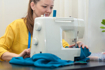 girl fashion designer sew. young dressmaker woman work in modern atelier for sewing machine. female tailor use measuring tape and making garments. Seamstress in workshop.